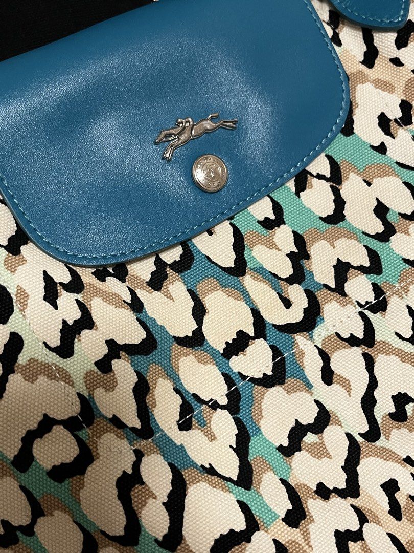 Longchamp Canvas Tote Bag (Category: Tote Bags) located in Cardona. Submitted by minyoonji (Listing ID 1469263575, Image 3). Description: - Brand: Longchamp - Design: All-over animal and leopard print in black, white, beige, and turquoise - Details: Blue leather shoulder handles and front flap closure with silver-tone snap button and embossed horse logo - Interior: Spacious fabric interior with open compartment - Condition: Clean fabric texture w