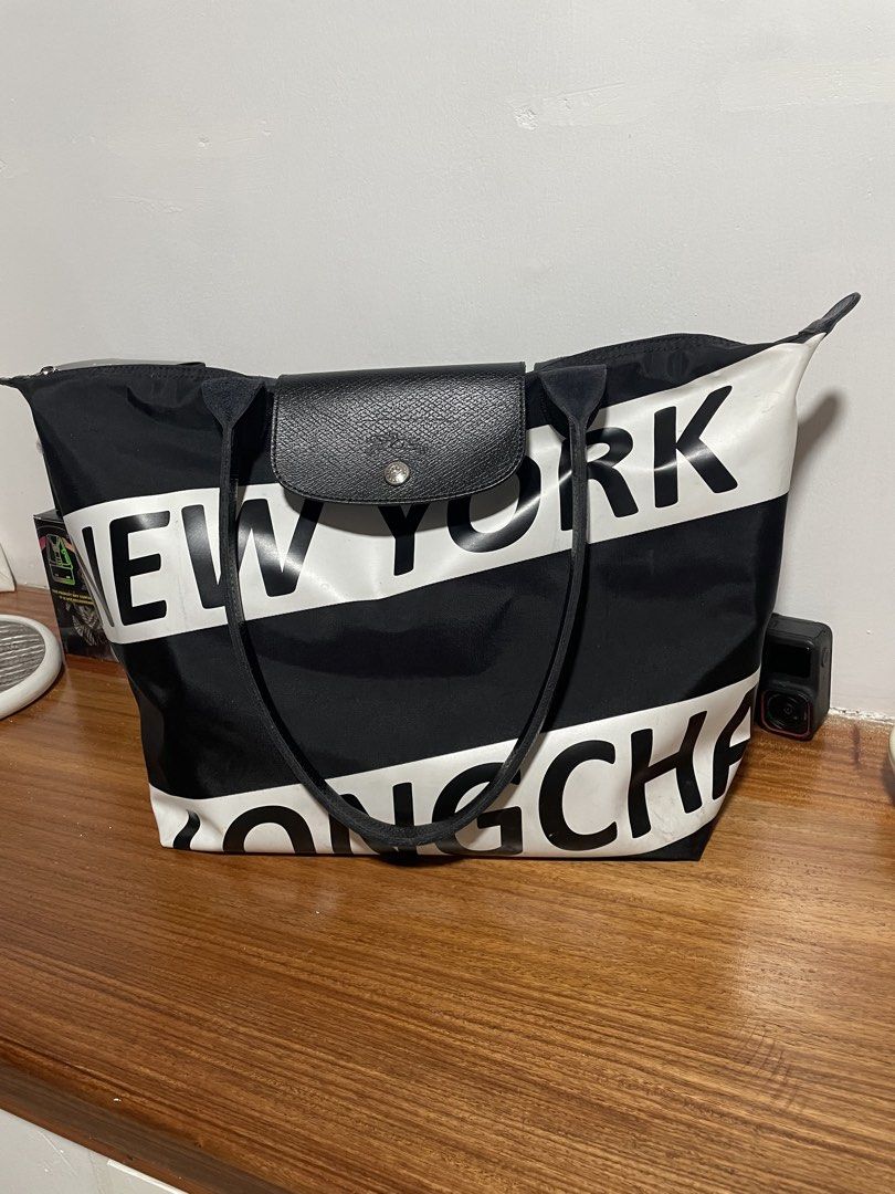 Longchamp le pliage large (Category: Tote Bags) located in Cainta. Submitted by sagepreloved (Listing ID 1469338192, Image 2). Description: Longchamp tote bag from the New York limited edition series. Bold white lettering across the black nylon body. Black leather handles and front flap closure with snap button. Top zip closure keeps items secure. Spacious interior handles daily essentials easily. Solid everyday carryall with standout graphic sty