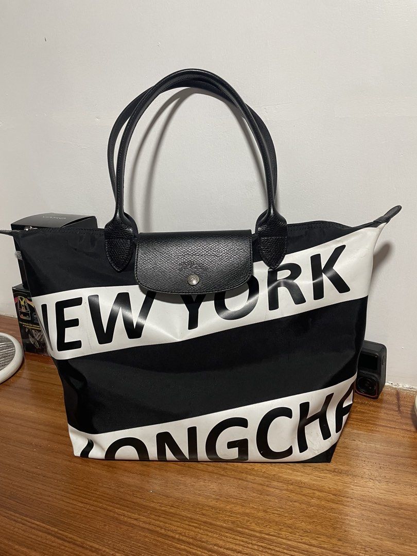 Longchamp le pliage large (Category: Tote Bags) located in Cainta. Submitted by sagepreloved (Listing ID 1469338192, Image 1). Description: Longchamp tote bag from the New York limited edition series. Bold white lettering across the black nylon body. Black leather handles and front flap closure with snap button. Top zip closure keeps items secure. Spacious interior handles daily essentials easily. Solid everyday carryall with standout graphic sty