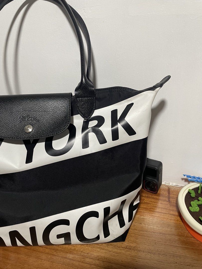 Longchamp le pliage large (Category: Tote Bags) located in Cainta. Submitted by sagepreloved (Listing ID 1469338192, Image 3). Description: Longchamp tote bag from the New York limited edition series. Bold white lettering across the black nylon body. Black leather handles and front flap closure with snap button. Top zip closure keeps items secure. Spacious interior handles daily essentials easily. Solid everyday carryall with standout graphic sty