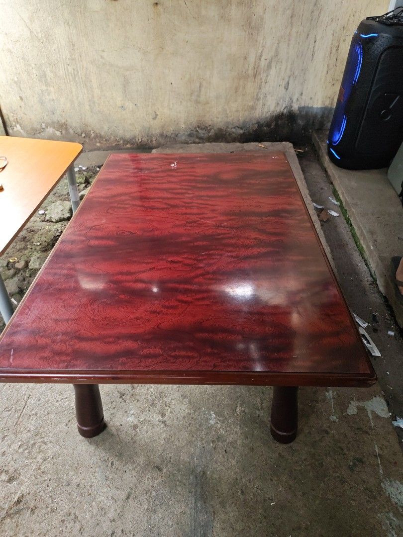 Low table japan surplus (Category: Tables & Sets) located in Manila. Submitted by aks_japansurplus30 (Listing ID 1469200144, Image 2). Description: - Type: Low wooden table / Floor seating table - Finish: Glossy reddish woodgrain top with smooth rounded edges - Legs: Dark brown turned legs with foldable metal brackets for easy storage - Condition: Sturdy and stable, with minor wear around the corner edges - Ideal for: Low living room setups, coff