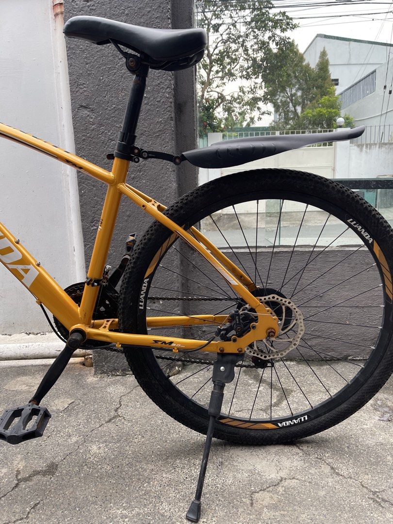 Luanda Mountain Bike Yellow (Category: Bicycles) located in Paranaque City. Submitted by cheskadejon (Listing ID 1469213183, Image 2). Description: - Bike: Yellow Luanda mountain bike - Brakes & Suspension: Front suspension fork and reliable disc brakes - Tires & Build: Rugged tires with a solid, functional frame featuring white branding - Extras included: Rear mudguard, kickstand, comfortable handlebar grips, and a small bell - Condition: Overal