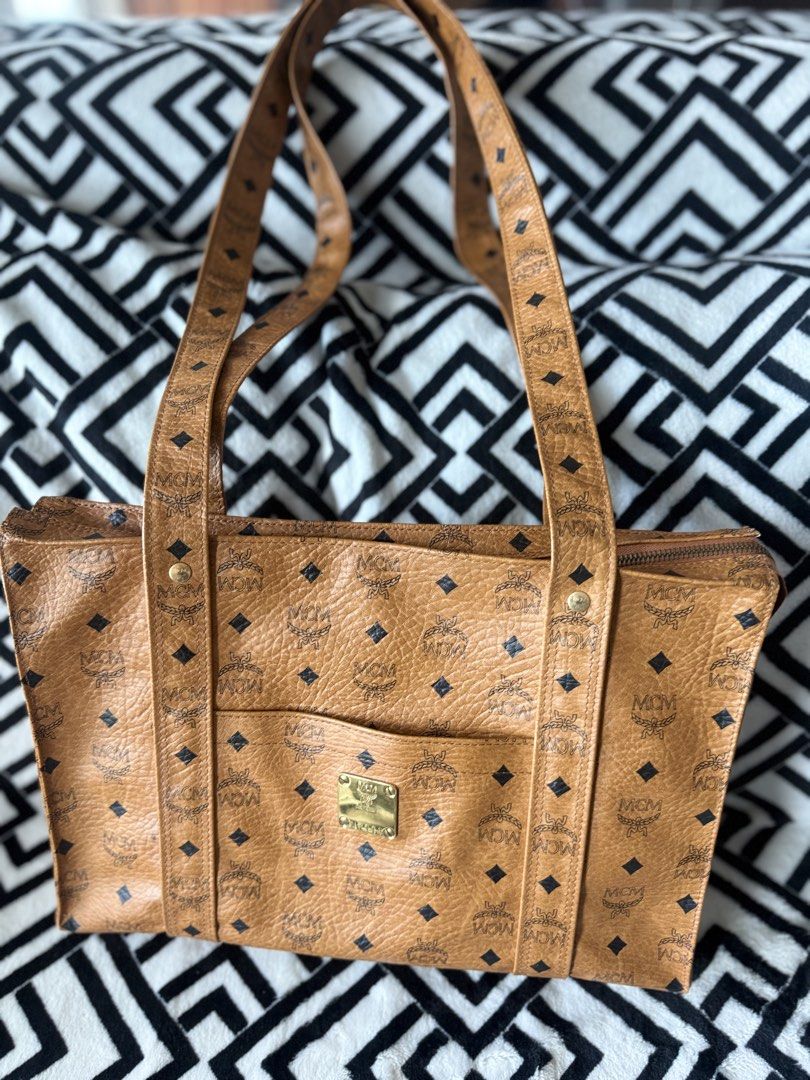 MCM Cognac Visetos Monogram Tote Bag (Category: Luxury Bags & Wallets) located in Pasig City. Submitted by sherill888 (Listing ID 1469338070, Image 2). Description: - Authentic MCM cognac Visetos monogram tote bag - Features double shoulder straps and a structured rectangular silhouette - Convenient front slip pocket with brass-tone logo plate (N7118) - Secure top zipper closure with metallic zipper pull - Crafted from signature coated canvas wit
