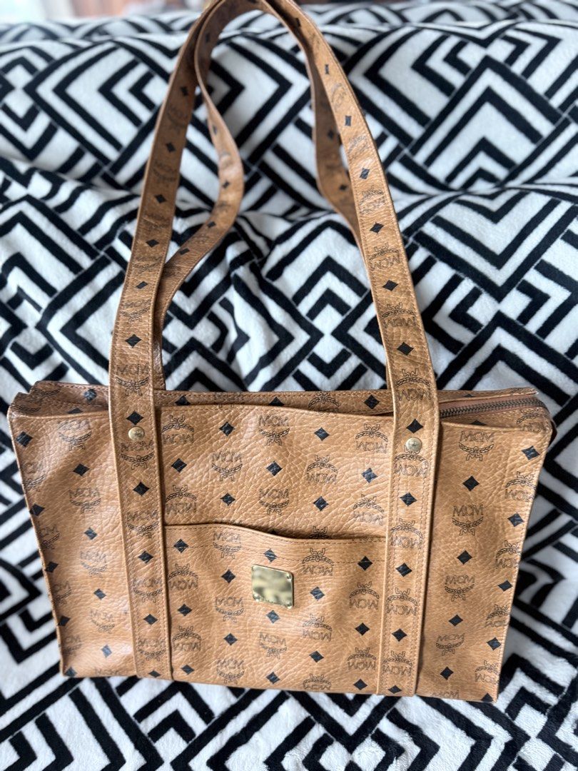 MCM Cognac Visetos Monogram Tote Bag (Category: Luxury Bags & Wallets) located in Pasig City. Submitted by sherill888 (Listing ID 1469338070, Image 1). Description: - Authentic MCM cognac Visetos monogram tote bag - Features double shoulder straps and a structured rectangular silhouette - Convenient front slip pocket with brass-tone logo plate (N7118) - Secure top zipper closure with metallic zipper pull - Crafted from signature coated canvas wit