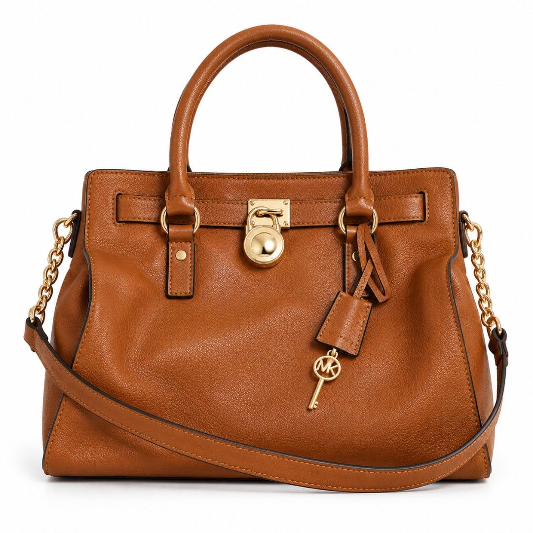 Michael Kors Brown Leather Satchel Handbag (Category: Luxury Bags & Wallets) located in Quezon City. Submitted by gorgeousvixen051893 (Listing ID 1469338331, Image 1). Description: - Brand: Michael Kors - Material: Premium tan brown pebbled leather - Hardware: Polished gold-tone hardware with signature padlock & key charm - Straps: Dual top handles and a removable strap with stylish chunky chain links - Interior: Secure zip-around style with grea