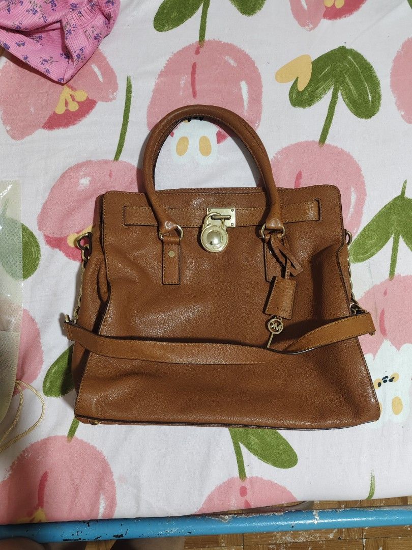 Michael Kors Brown Leather Satchel Handbag (Category: Luxury Bags & Wallets) located in Quezon City. Submitted by gorgeousvixen051893 (Listing ID 1469338331, Image 3). Description: - Brand: Michael Kors - Material: Premium tan brown pebbled leather - Hardware: Polished gold-tone hardware with signature padlock & key charm - Straps: Dual top handles and a removable strap with stylish chunky chain links - Interior: Secure zip-around style with grea