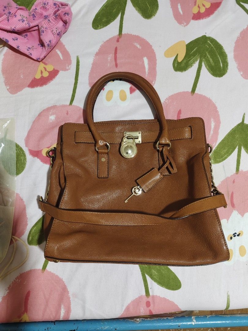 Michael Kors Brown Leather Satchel Handbag (Category: Luxury Bags & Wallets) located in Quezon City. Submitted by gorgeousvixen051893 (Listing ID 1469338331, Image 2). Description: - Brand: Michael Kors - Material: Premium tan brown pebbled leather - Hardware: Polished gold-tone hardware with signature padlock & key charm - Straps: Dual top handles and a removable strap with stylish chunky chain links - Interior: Secure zip-around style with grea