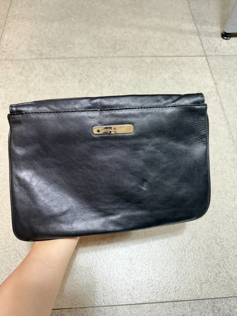 Michael Kors Double-Flap Leather Clutch (Category: Luxury Bags & Wallets) located in Malabon City. Submitted by angelamaclan (Listing ID 1469243475, Image 2). Description: Black leather clutch bag from Michael Kors. Double flap closure secured with a magnetic snap button. The back features a metal Michael Kors logo plaque. Soft leather texture with minimal wear..