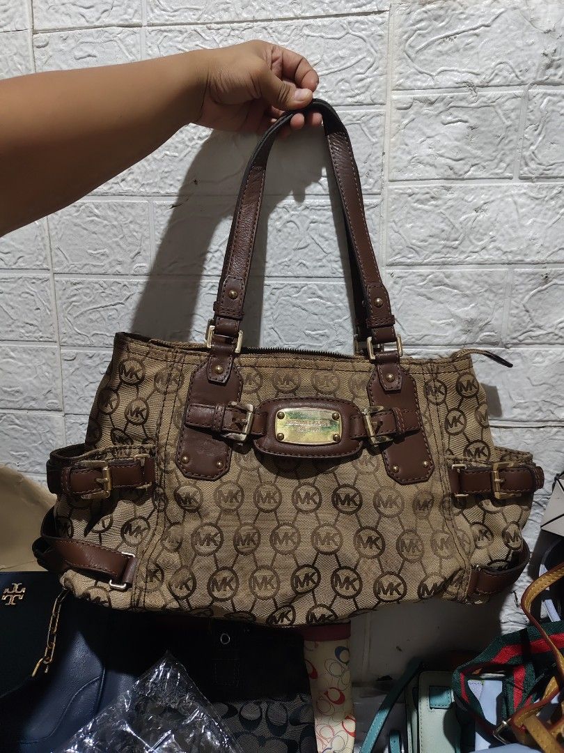 Michael Kors Vintage Gansevoort (Category: Luxury Bags & Wallets) located in Caloocan City. Submitted by danicamae35900 (Listing ID 1469211462, Image 1). Description: Brown canvas shoulder bag with allover MK monogram print. Leacther handles and trim in dark brown. Gold-tone hardware with Michael Kors engraved plaque on front. Buckle details on the sides and front. Zipper closure at top. Double shoulder straps. Roomy interior..