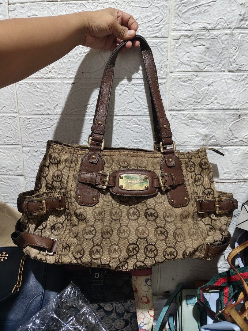 Michael Kors Vintage Gansevoort (Category: Luxury Bags & Wallets) located in Caloocan City. Submitted by danicamae35900 (Listing ID 1469211462, Image 2). Description: Brown canvas shoulder bag with allover MK monogram print. Leacther handles and trim in dark brown. Gold-tone hardware with Michael Kors engraved plaque on front. Buckle details on the sides and front. Zipper closure at top. Double shoulder straps. Roomy interior..