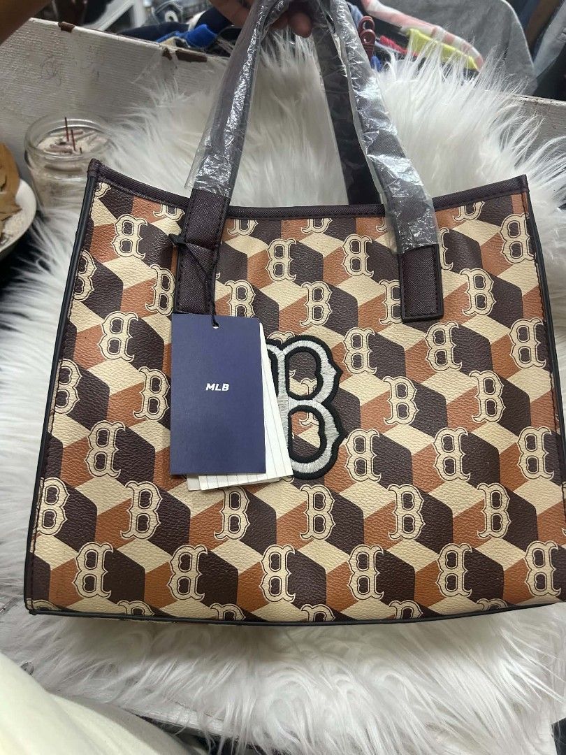 MLB Brown Monogram Tote Bag with Strap (Category: Tote Bags) located in Manila. Submitted by kkiato (Listing ID 1469283568, Image 2). Description: - Stylish brown and beige MLB monogram cube print tote bag - Dual top handles wrapped in protective plastic for safekeeping - Includes a detachable matching shoulder strap for versatile wear - Main interior compartment equipped with a secure zipper side pocket - Clean interior lining with original bran