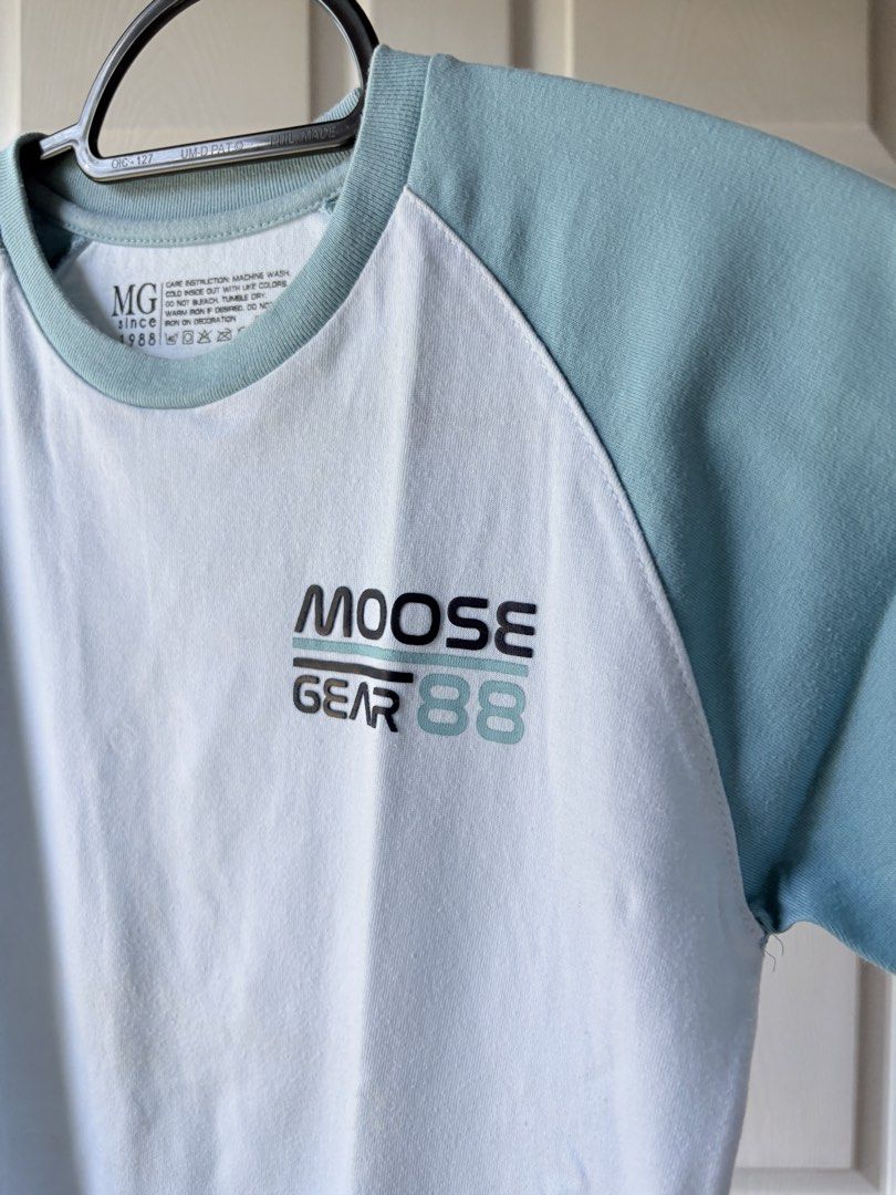 Moose Gear 88 Raglan T-Shirt (Category: Babies & Kids Fashion) located in Liloan. Submitted by mrs.jboiser (Listing ID 1469206373, Image 3). Description: - Brand: Moose Gear - Style: Raglan short-sleeve t-shirt with crew neck - Color: White body with light blue sleeves and collar - Design: Small printed graphic on the left chest - Material: Soft and breathable cotton knit - Comfort: Clean interior heat-pressed neck tag (no scratchy labels) - Care