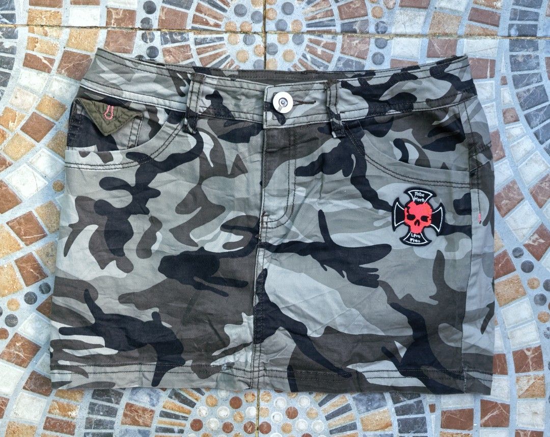 MXE Camouflage Mini Skirt Size 27 (Category: Skirts) located in Quezon. Submitted by miksxthrift (Listing ID 1469276541, Image 1). Description: - Brand: MXE - Style: Camouflage utility mini skirt with street style vibe - Size: 27 waist - Colorway: Green, brown, and grey tones - Details: Front pockets, buttoned back flap pockets, red skull patch on the front right, and belt loops - Closure: Front button closure - Material: Comfortable cotton blend
