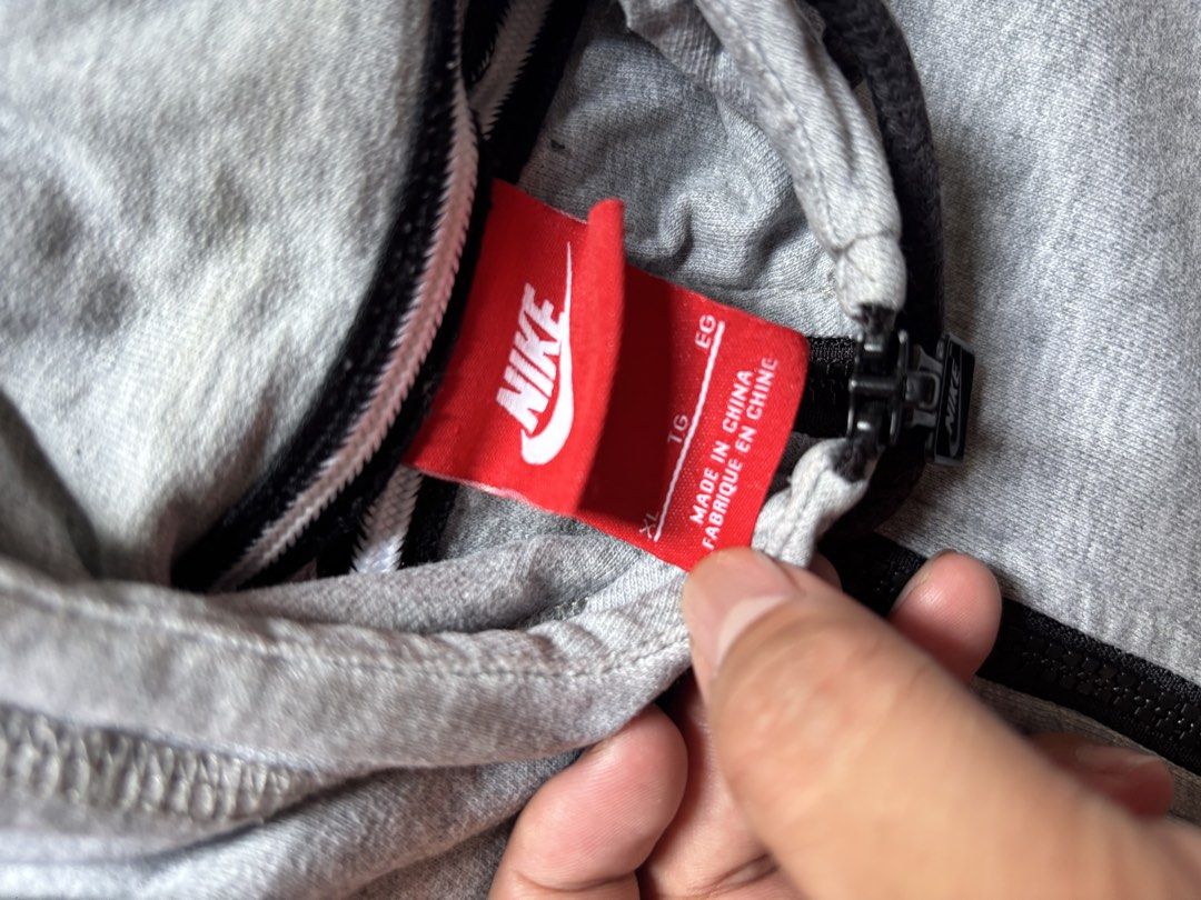 Nike Grey Zip Hoodie Size XL (Category: Hoodies) located in Caloocan City. Submitted by keepinhighl (Listing ID 1469232264, Image 3). Description: XL on tag 28x23 - Brand: Nike - Color: Grey with red interior neck tag - Size: XL (Regular Fit) - Material: Comfortable cotton blend, great for daily wear - Details: Nike-branded zipper pull, ribbed black hood drawstrings - Origin: Made in China.