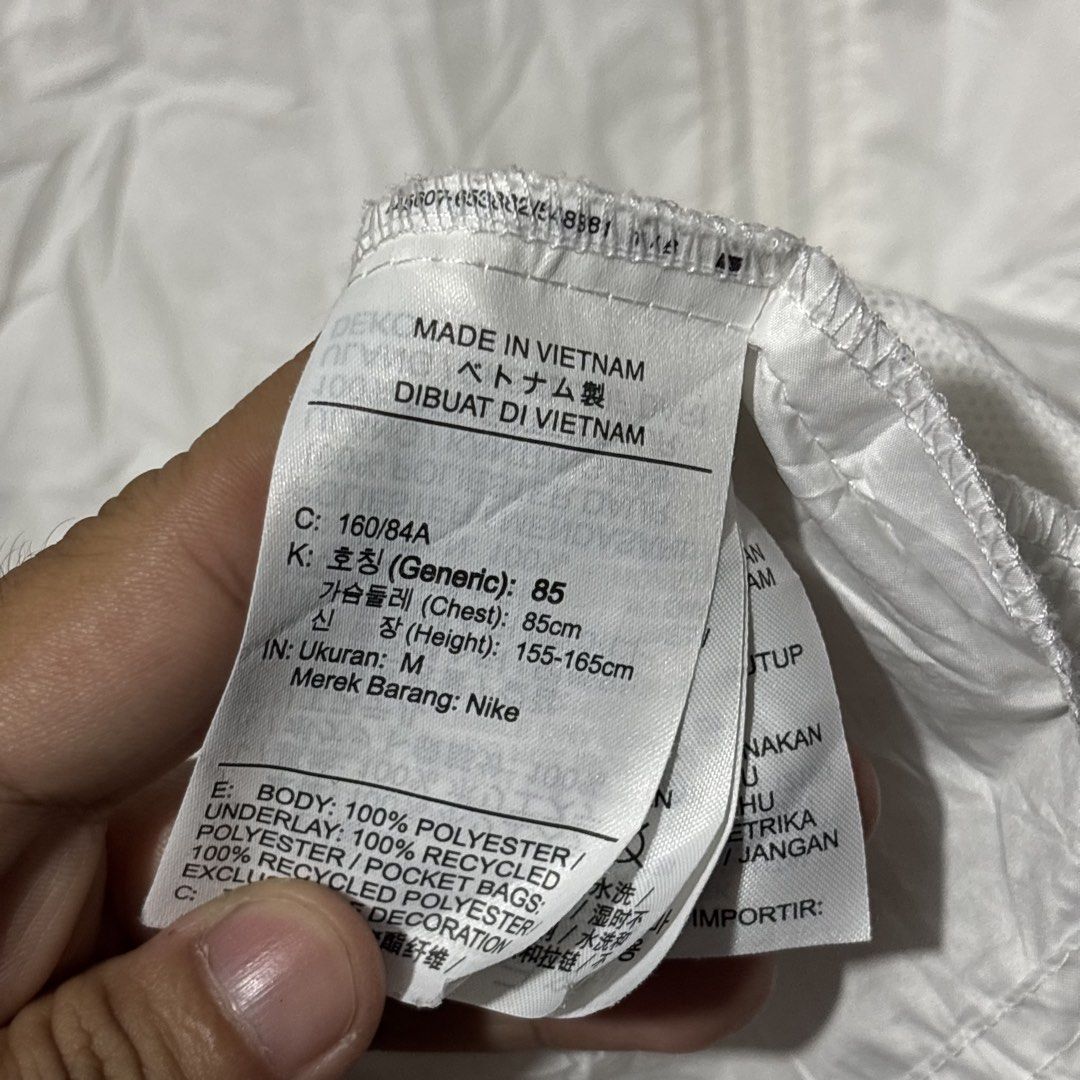 Nike White Windbreaker Jacket (Category: Coats, Jackets and Outerwear) located in Caloocan City. Submitted by bonsatocha43876 (Listing ID 1469322782, Image 3). Description: - Brand: Nike - Item: White Windbreaker Jacket - Size: Medium (Width: 20 inches, Length: 26 inches) - Material: 100% polyester body with recycled polyester underlay - Origin: Made in Vietnam - Features: Full zip closure, adjustable drawstring hood, and classic black Nike swoos