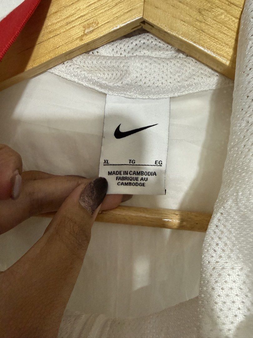 Nike Windbreaker Jacket White Red Black Size XL (Category: Coats, Jackets and Outerwear) located in Quezon City. Submitted by dapanaaaay (Listing ID 1469347994, Image 2). Description: - Brand: Nike (Style Code: DJ5727-100) - Size: XL - Color: White, Red, and Black - Design: Iconic Big Swoosh logo across the chest - Features: Half-zip neck with hood, front kangaroo pocket with zippered section, ribbed cuffs and hem - Material: Lightweight fabric w