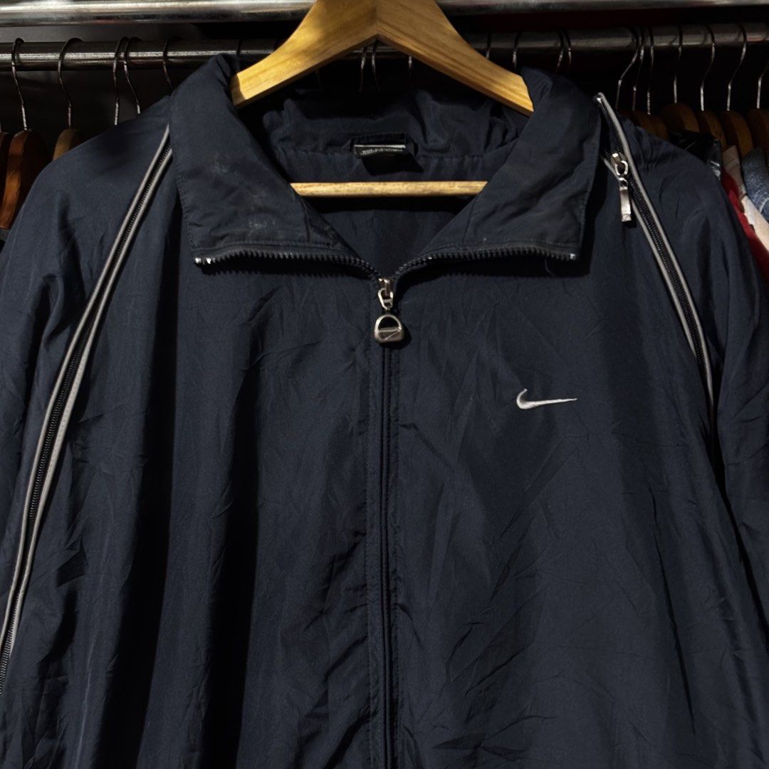 Nike Windbreaker Navy Blue (Category: Coats, Jackets and Outerwear) located in Caloocan City. Submitted by bonsatocha43876 (Listing ID 1469321077, Image 3). Description: - Brand: Nike - Color: Navy blue - Material: 100% nylon (Made in Indonesia) - Size/Fit: Width 25" x Length 31" - Design: Full zip front with custom branded zipper pull, iconic Nike swoosh embroidery on the chest, and stylish piping along the shoulders and sleeves - Storage: Dual 
