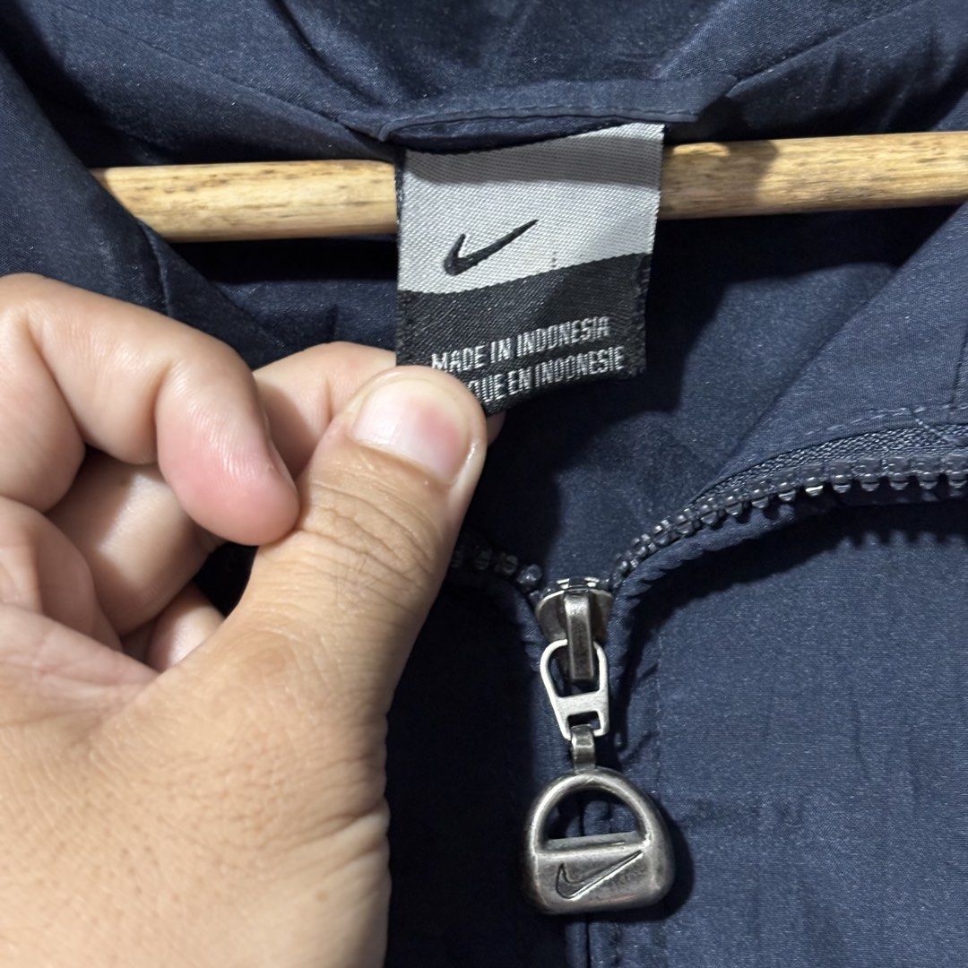 Nike Windbreaker Navy Blue (Category: Coats, Jackets and Outerwear) located in Caloocan City. Submitted by bonsatocha43876 (Listing ID 1469321077, Image 2). Description: - Brand: Nike - Color: Navy blue - Material: 100% nylon (Made in Indonesia) - Size/Fit: Width 25" x Length 31" - Design: Full zip front with custom branded zipper pull, iconic Nike swoosh embroidery on the chest, and stylish piping along the shoulders and sleeves - Storage: Dual 