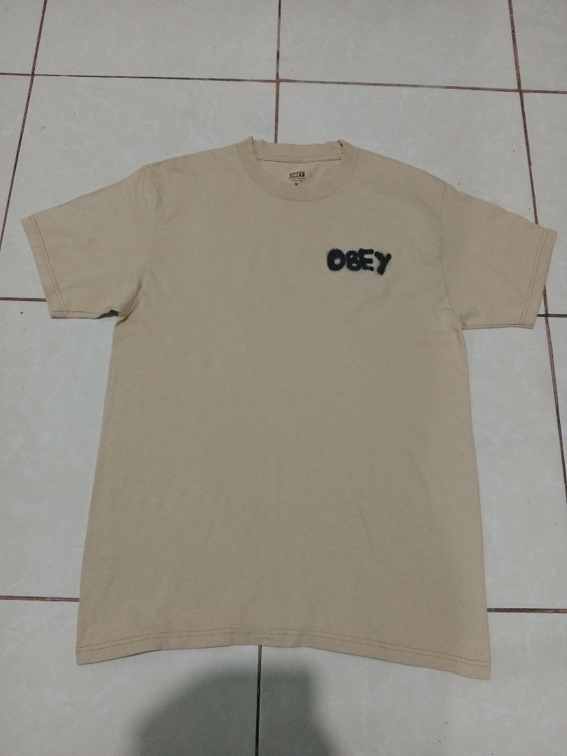 Obey Visual Design Studio Spray Logo T-Shirt Cream (Category: Tshirts & Polo Shirts ) located in Bacolod City. Submitted by jorengrate26639 (Listing ID 1469327113, Image 1). Description: - Brand: Obey - Color: Cream - Size: Medium - Material: 100% cotton, made in Mexico - Design: Black spray-paint logo on chest, large Obey Visual Design Studio graphic on the back - Fit: Standard fit, short sleeves, crew neck - Style: Casual streetwear - Condition