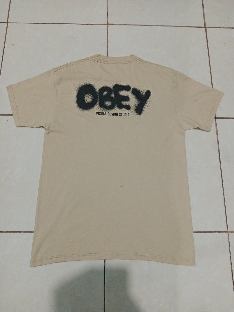 Obey Visual Design Studio Spray Logo T-Shirt Cream (Category: Tshirts & Polo Shirts ) located in Bacolod City. Submitted by jorengrate26639 (Listing ID 1469327113, Image 2). Description: - Brand: Obey - Color: Cream - Size: Medium - Material: 100% cotton, made in Mexico - Design: Black spray-paint logo on chest, large Obey Visual Design Studio graphic on the back - Fit: Standard fit, short sleeves, crew neck - Style: Casual streetwear - Condition