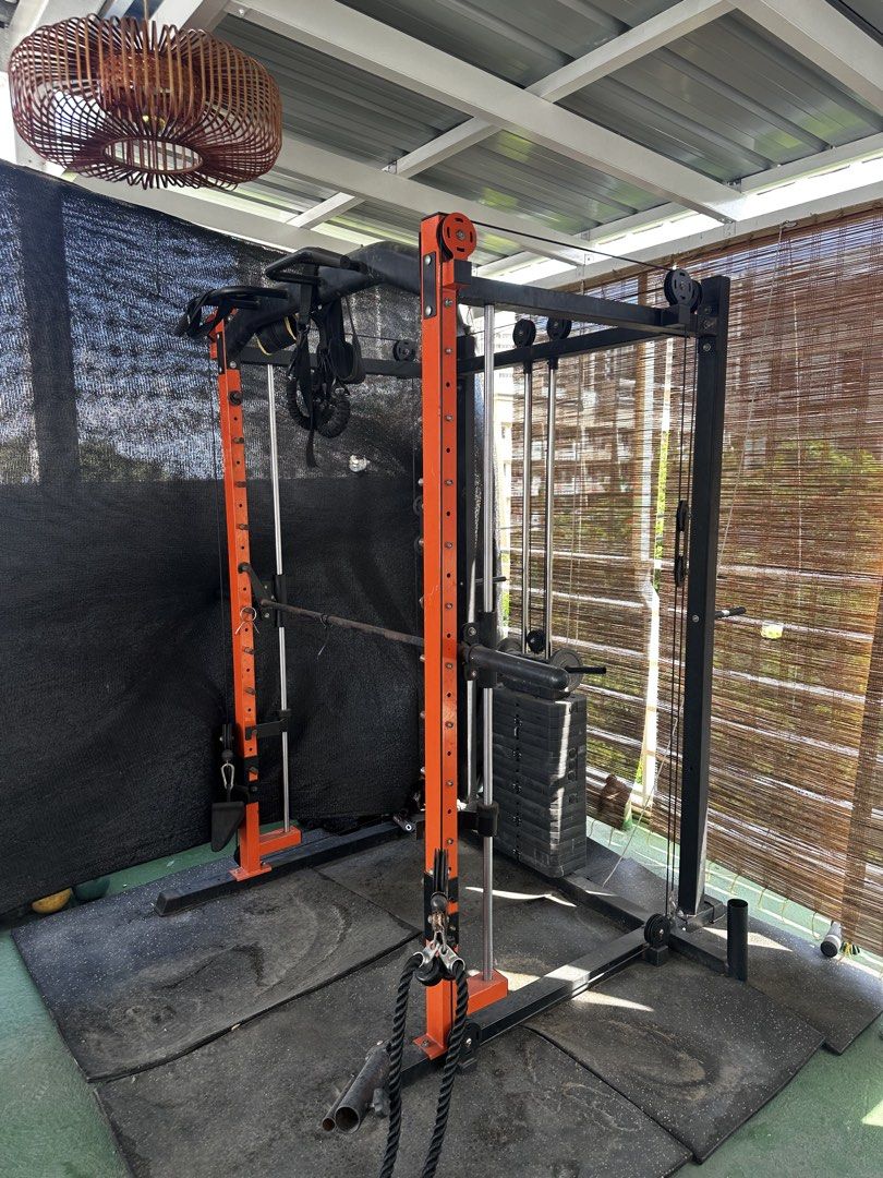Orange and Black Smith Machine Power Cage with Cable Crossover (Category: Cardio & Fitness Machines) located in Pasig City. Submitted by hernandez2001 (Listing ID 1469273419, Image 2). Description: Complete home gym setup featuring a Smith machine, dual cable pulley, and pull-up bar. Heavy-duty orange and black steel frame with rubber flooring mats included. Perfect for full-body workouts. Buyer must dismantle upon pickup. PM for details!.