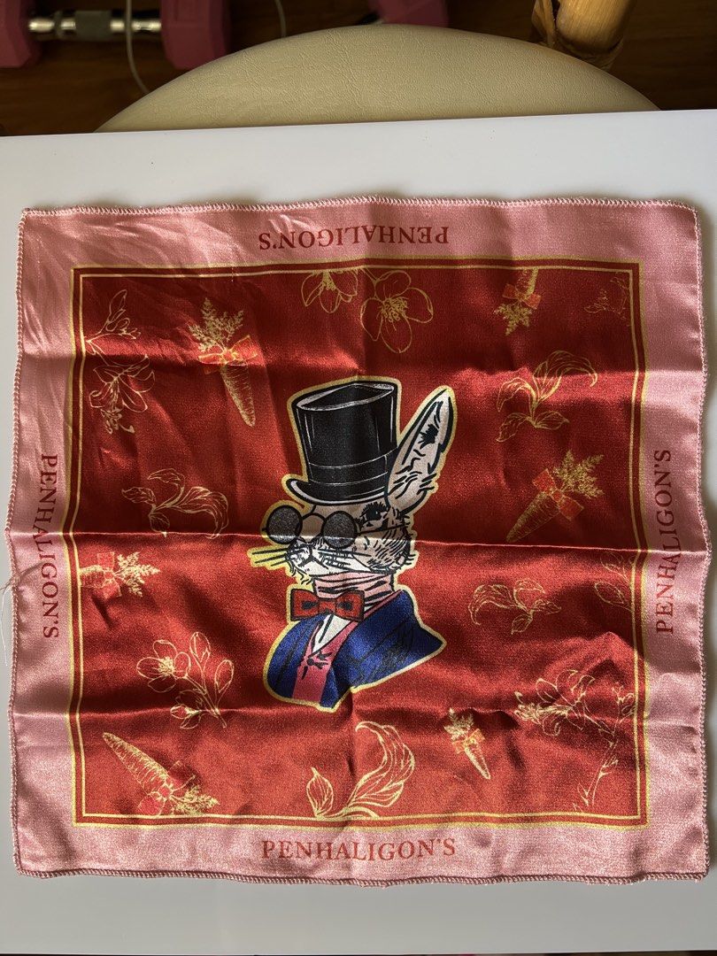 Penhaligon's Rabbit Print Silk Pocket Square Scarf (Category: Scarves) located in Rizal. Submitted by s0apandglory (Listing ID 1469171998, Image 1). Description: - Brand: Penhaligon's - Design: Gentleman rabbit in top hat and round glasses with gold carrots and floral accents - Colorway: Deep red center panel with a vibrant pink border - Details: Brand name printed along all four sides - Material: Soft satin-like silk finish with hand-rolled edge