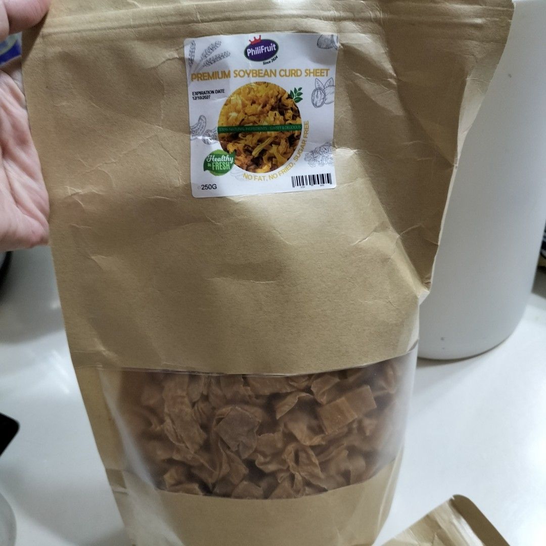 Premium Soybean Curd Sheet 250G (Category: Fresh Produce) located in Paranaque City. Submitted by decluttering-all (Listing ID 1469193182, Image 3). Description: - Product: PhiliFruit Soybean Curd Sheet in flat noodles - Weight: 250g in a brown paper bag with a clear window - Health Benefits: Healthy, fresh, zero fat, non-fried, and sugar-free - Condition: Brand new, sealed, and unopened packaging - Expiration Date: 12/10/2027 p100 per pack of 25