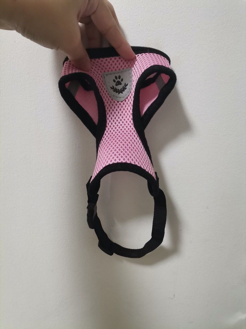 Pink Mesh Pet Harness Size S (Category: Sleeveless) located in Makati City. Submitted by kookybearsstuff (Listing ID 1469278754, Image 1). Description: - Color: Pink with black trim - Size: S (tag attached) - Material: Breathable mesh - Safety: Reflective strips on the sides for night walks - Hardware: Sturdy metal D-ring for leash attachment - Closure: Secure plastic buckle - Details: Adorable paw print badge on the front.