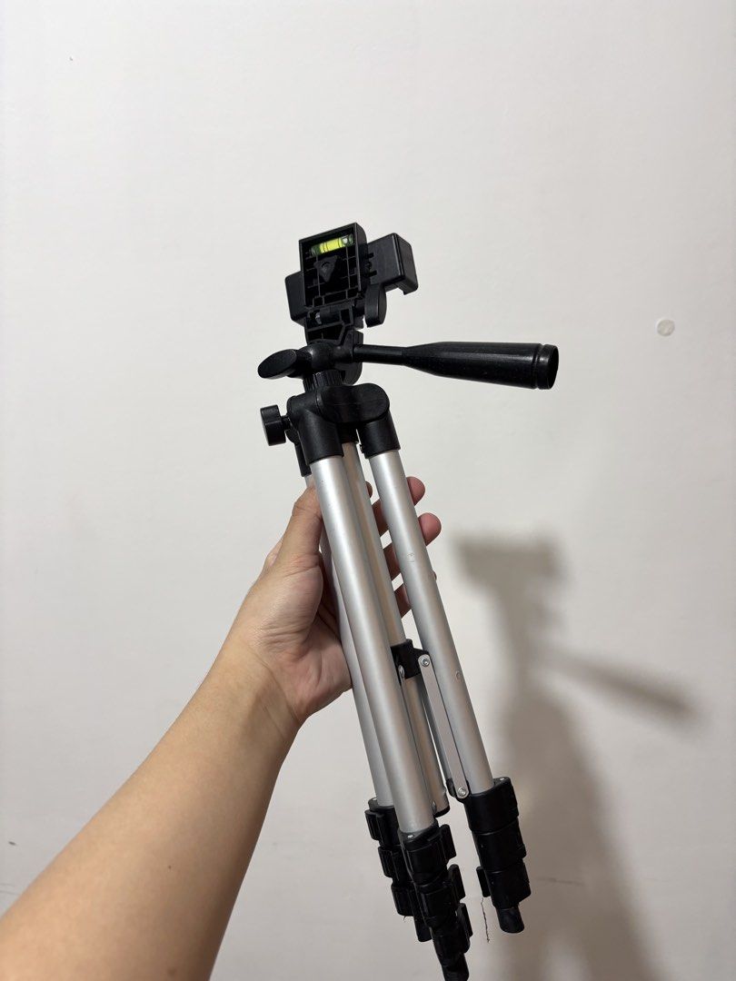 Portable Aluminum Tripod (Category: Tripods & Monopods) located in Bulacan. Submitted by janeeeeelleeeee (Listing ID 1469304328, Image 2). Description: - Material: Lightweight aluminum - Compatibility: Standard mount for cameras and smartphones - Adjustability: Extendable legs with quick-flip locks - Head: Pan head with adjustment handle and built-in bubble level - Portability: Folds down compactly for travel and daily vlogging - Condition: Clean