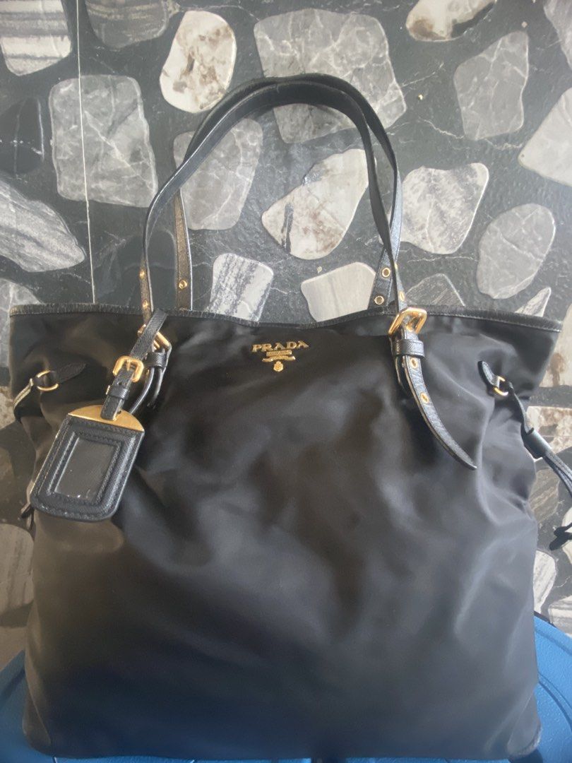 Prada Black Nylon Tote Bag (Category: Luxury Bags & Wallets) located in Bacolod City. Submitted by chuchaystuffs (Listing ID 1469165863, Image 1). Description: - Authentic black nylon Prada tote bag - Elegant Saffiano leather handles and gold-tone hardware - Iconic gold Prada logo on the front - Classic design with stylish double buckled straps - Includes a matching luggage tag - Spacious interior, perfect for carrying daily essentials.