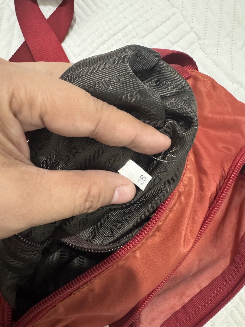 Prada Red Nylon Crossbody Flap Bag (Category: Luxury Bags & Wallets) located in Koronadal. Submitted by milagraciaukayukay123_. (Listing ID 1469296607, Image 2). Description: - Authentic red nylon Prada crossbody bag - Features iconic silver-tone triangular logo plaque and durable Lampo zipper hardware - Adjustable strap for comfortable wear - Front flap with secure buckle closure and convenient front pocket - Zippered main compartment with dark 