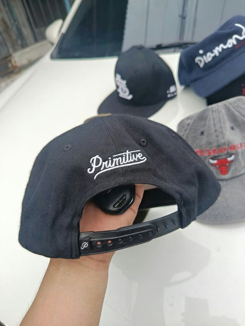 Primitive Black Snapback Cap (Category: Caps & Hats) located in Caloocan City. Submitted by happyeagle-e816c5 (Listing ID 1469262758, Image 2). Description: - Brand: Primitive - Color: Black with white embroidery - Design: Large front script logo & back embroidery - Brim: Flat brim with unique patterned texture - Fit: Standard fit with adjustable plastic snapback closure - Style: Casual / Streetwear - Condition: Excellent / Pre-loved (as good as 