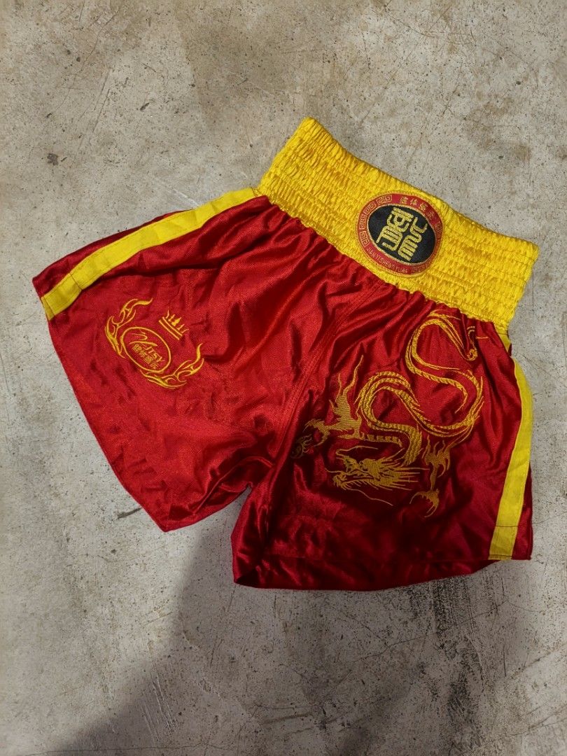 Red and Gold Dragon Boxing Short (Category: Combat Sports) located in Manila. Submitted by raihusling (Listing ID 1469315215, Image 1). Description: - Premium red and gold lightweight satin fabric - Wide elastic waistband with central embroidered dragon patch - Intricate gold dragon embroidery on the right leg - Smaller logo emblem on the left leg - Stylish bright yellow side stripes - Traditional style suitable for martial arts training or compe