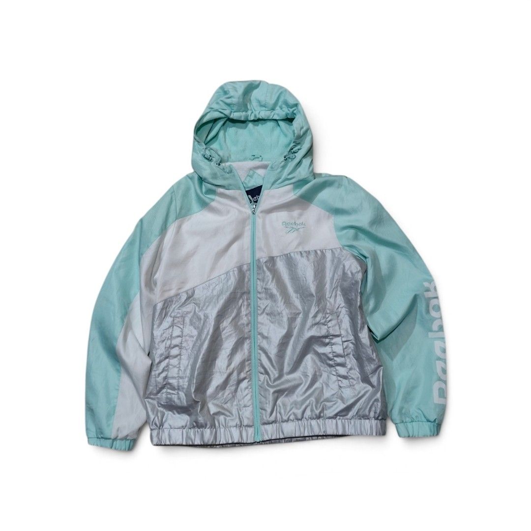 Reebok Colorblock Windbreaker Jacket Mint Silver White (Category: Coats, Jackets and Outerwear) located in Taguig. Submitted by lloydyy_thrift (Listing ID 1469322680, Image 1). Description: - Brand: Reebok - Colorway: Mint green, white, and silver colorblock - Closure: Full zip front with matching pull - Hood: Adjustable with drawstring - Branding: Reebok logo on chest and large lettering down left sleeve - Pockets: Two functional front pockets -