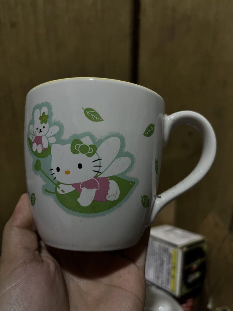 Sanrio Hello Kitty 2002 Green Leaf Ceramic Mug (Category: Coffee & Tea Tableware) located in Manila. Submitted by janetecson05 (Listing ID 1469251313, Image 1). Description: - Official Sanrio merchandise (dated 1976 & 2002) - Cute design featuring Kitty with fairy wings and green leaves - Stylish yellow interior rim - Comfortable C-handle for easy grip - Perfect addition to any Kitty or Sanrio collection.