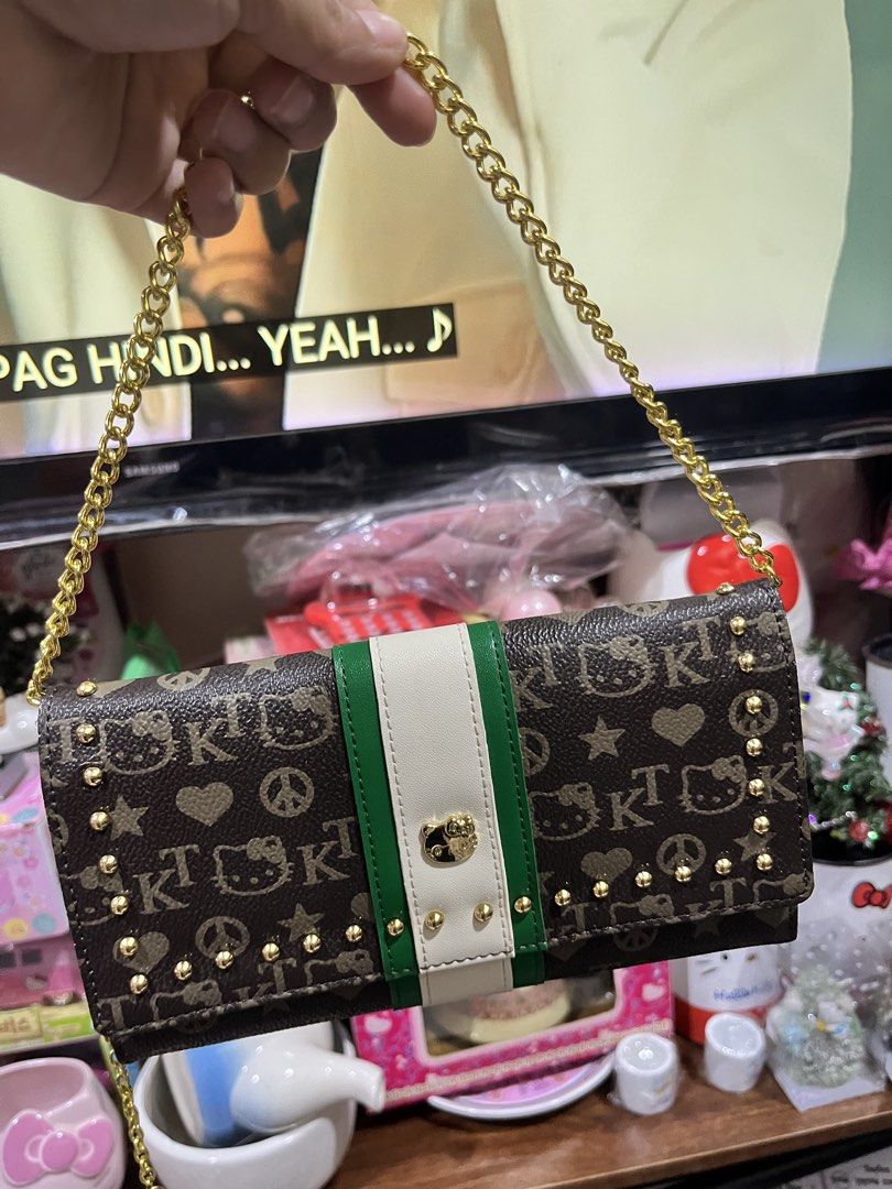 Sanrio Hello Kitty Monogram Wallet with Chain Strap (Category: Wallets & Card holders) located in Manila. Submitted by janetecson05 (Listing ID 1469194414, Image 1). Description: HK VIVITIX LONG WALLET - Authentic Sanrio Kitty long wallet - Chic brown monogram print with a sporty green & white center stripe - Luxurious gold metallic interior lining with multiple card slots and compartments - Secure snap button closure - Includes a detachable gold
