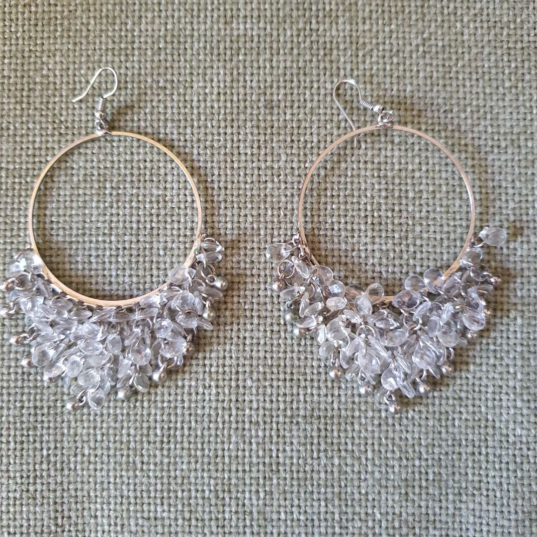 Silver Beaded Hoop Dangle Earrings (Category: Earrings) located in Caloocan City. Submitted by mma_222 (Listing ID 1469197762, Image 1). Description: - Style: Large silver hoop earrings with hanging beaded fringe - Design: Triangle dangle shape featuring clear faceted beads and small silver spheres - Closure: Silver-toned fishhook closures - Comfort: Lightweight design for all-day wear - Versatility: Great statement piece for evening outings or c