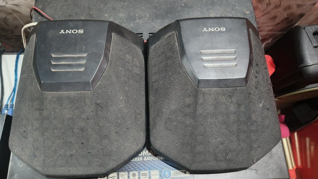 Sony SS-SR991 mini surround speakers (Category: Soundbars, Speakers & Amplifiers) located in Batangas. Submitted by riyanasiafashionshop (Listing ID 1469330078, Image 1). Description: Key Details & Condition Design: These compact, pentagonal-shaped speaker enclosures are wrapped in black fabric mesh grills. They feature distinct silver accents at the top embossed with the SONY logo and three horizontal vent-style decorative lines. Application: Th