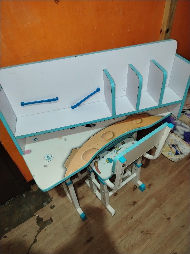 Space theme kids study table and matching chair set (Category: Kids Tables & Chairs) located in Manila. Submitted by nesacake (Listing ID 1469335387, Image 2). Description: - Kids study table and matching chair set with fun space exploration theme (astronauts, rockets, planets) - White surfaces with blue edges and matching space print seat - Includes attached hutch with built-in bookshelf compartments and holders - Sturdy metal frame with adjusta