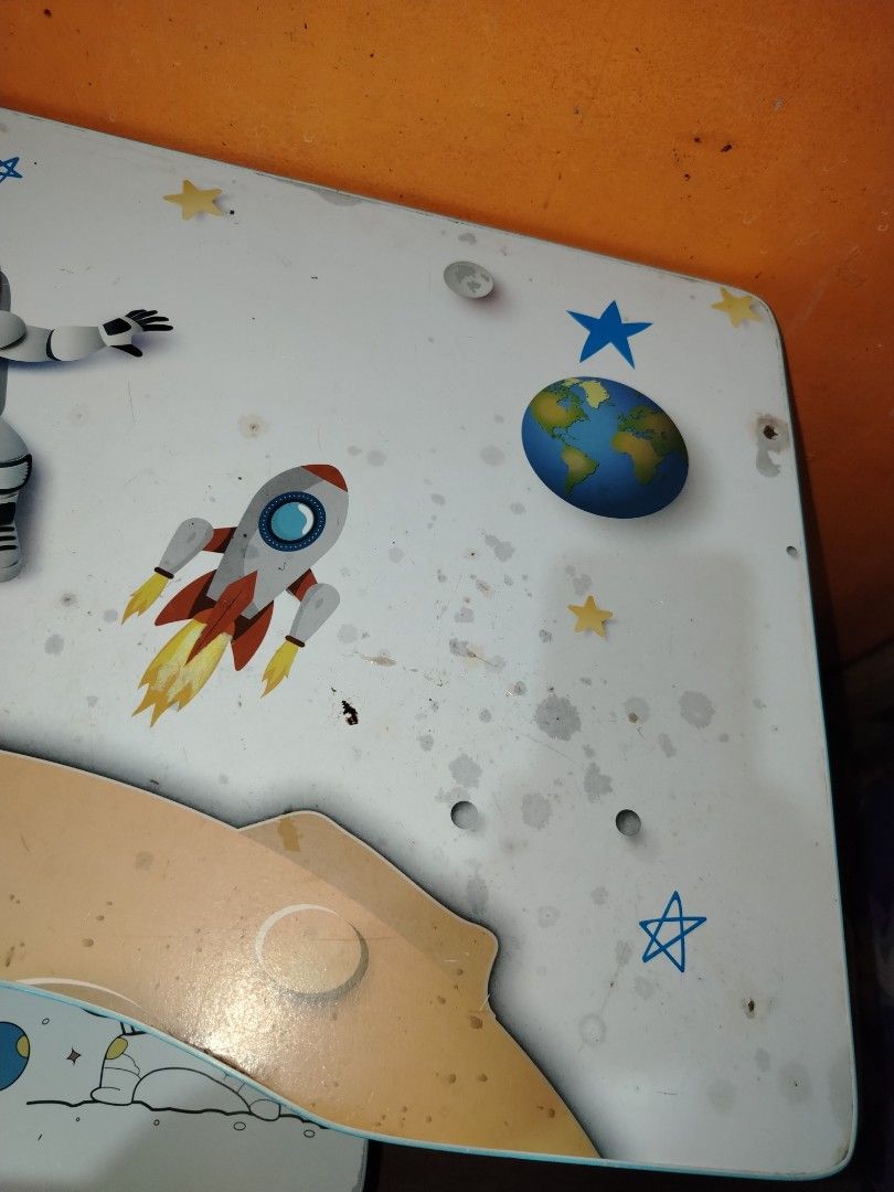 Space theme kids study table and matching chair set (Category: Kids Tables & Chairs) located in Manila. Submitted by nesacake (Listing ID 1469335387, Image 3). Description: - Kids study table and matching chair set with fun space exploration theme (astronauts, rockets, planets) - White surfaces with blue edges and matching space print seat - Includes attached hutch with built-in bookshelf compartments and holders - Sturdy metal frame with adjusta