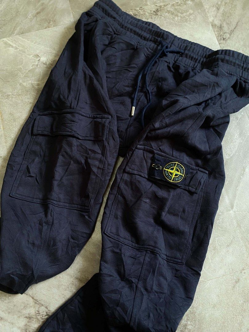 Stone Island Navy Blue Cargo Sweatpants (Category: Joggers) located in Butuan. Submitted by jc13thrifts (Listing ID 1469342565, Image 2). Description: - Brand: Stone Island - Color: Navy Blue - Material: Comfortable, high-quality cotton - Waist: Elastic waistband with adjustable drawstring - Pockets: Functional side cargo pockets and a back pocket - Signature Detail: Iconic yellow compass badge on the left leg - Cuffs: Ribbed ankles for a snug fi