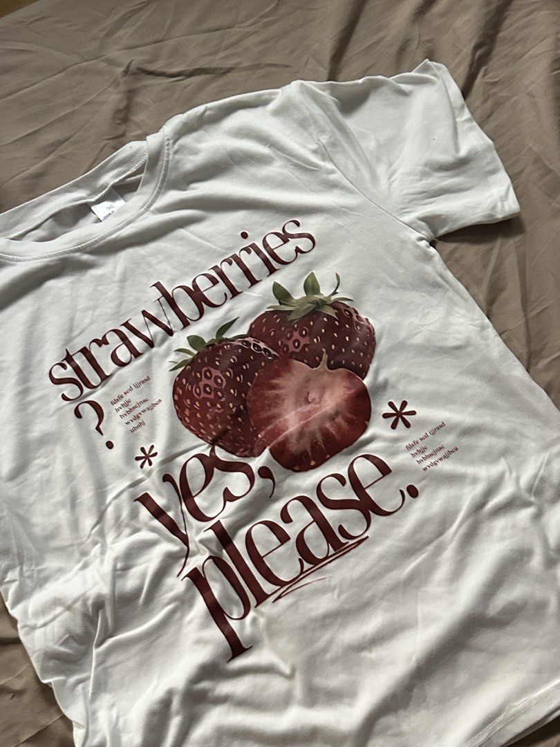 Strawberries Graphic T-Shirt (Category: Shirts) located in Rizal. Submitted by nixx__ (Listing ID 1469163967, Image 2). Description: - Color: White - Design: Large strawberry graphic print with 'strawberries yes please' text and decorative symbols - Fit: Classic crew neck with short sleeves - Material: Soft and breathable cotton - Quality: Neat stitching along hems - Condition: Brand new with tag.