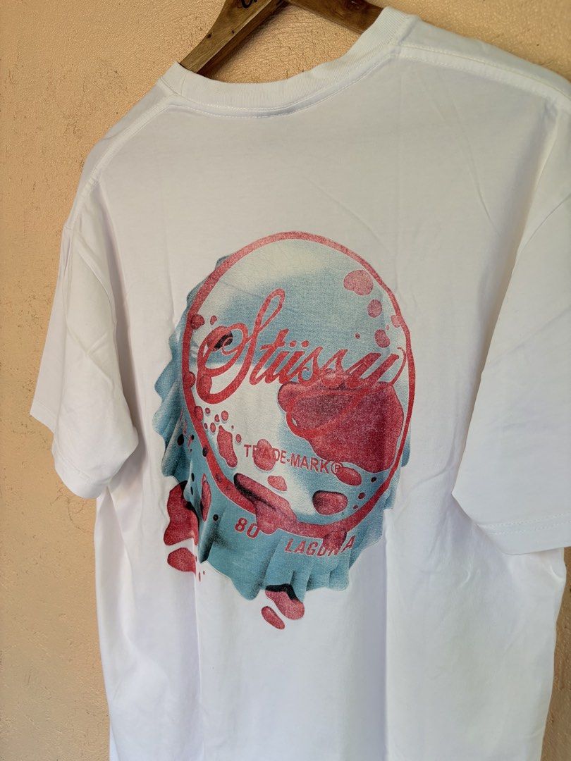 Stüssy 80 Laguna Graphic Tee White Size L (Category: Tshirts & Polo Shirts ) located in Pozorrubio. Submitted by zionegotthrift (Listing ID 1469200664, Image 2). Description: - Brand: Stüssy - Color: White - Size: Large - Material: 100% Cotton (Made in Mexico) - Design: Small script logo on left chest, big liquid bubble '80 Laguna' graphic on the back - Fit: Standard crew neck short sleeve.