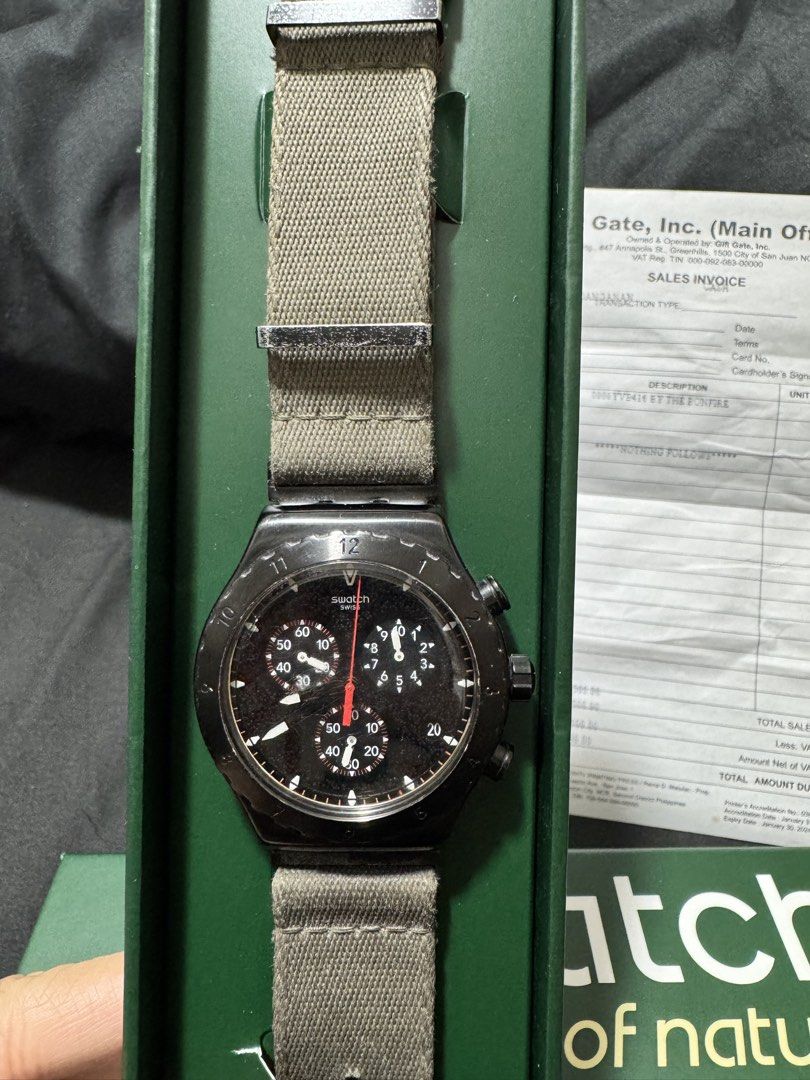 Swatch Irony Chrono By The Bonfire (Category: Men's Watches) located in Cavite. Submitted by mrswitchfoot (Listing ID 1469392729, Image 3). Description: - Model: Swatch Irony Chrono By The Bonfire (YVB416) - Dial: Black with textured 3D details and striking red and white print - Case: Brushed stainless steel with a sleek black PVD coating - Strap: Durable green textile strap with metal loops - Inclusions: Complete with original green box and offi