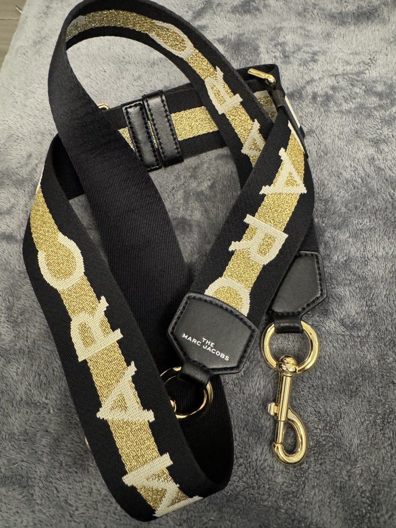 The Marc Jacobs Webbing Strap Black Gold (Category: Luxury Bags & Wallets) located in Taguig. Submitted by sqaumejada (Listing ID 1469176774, Image 2). Description: - Brand: The Marc Jacobs - Color: Black and Gold - Material: Thick woven fabric with leather trim - Hardware: Shiny gold-tone with swivel clasps - Features: Branded lettering and adjustable slider buckle - Condition: Excellent, like new - Note: Great for customizing and giving your fa
