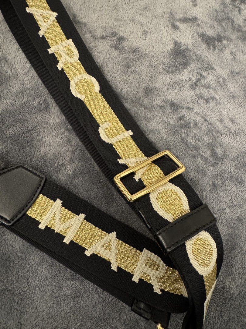 The Marc Jacobs Webbing Strap Black Gold (Category: Luxury Bags & Wallets) located in Taguig. Submitted by sqaumejada (Listing ID 1469176774, Image 1). Description: - Brand: The Marc Jacobs - Color: Black and Gold - Material: Thick woven fabric with leather trim - Hardware: Shiny gold-tone with swivel clasps - Features: Branded lettering and adjustable slider buckle - Condition: Excellent, like new - Note: Great for customizing and giving your fa
