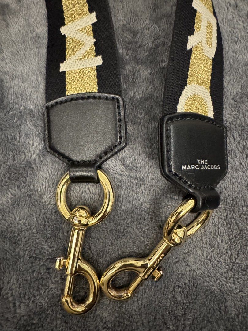 The Marc Jacobs Webbing Strap Black Gold (Category: Luxury Bags & Wallets) located in Taguig. Submitted by sqaumejada (Listing ID 1469176774, Image 3). Description: - Brand: The Marc Jacobs - Color: Black and Gold - Material: Thick woven fabric with leather trim - Hardware: Shiny gold-tone with swivel clasps - Features: Branded lettering and adjustable slider buckle - Condition: Excellent, like new - Note: Great for customizing and giving your fa