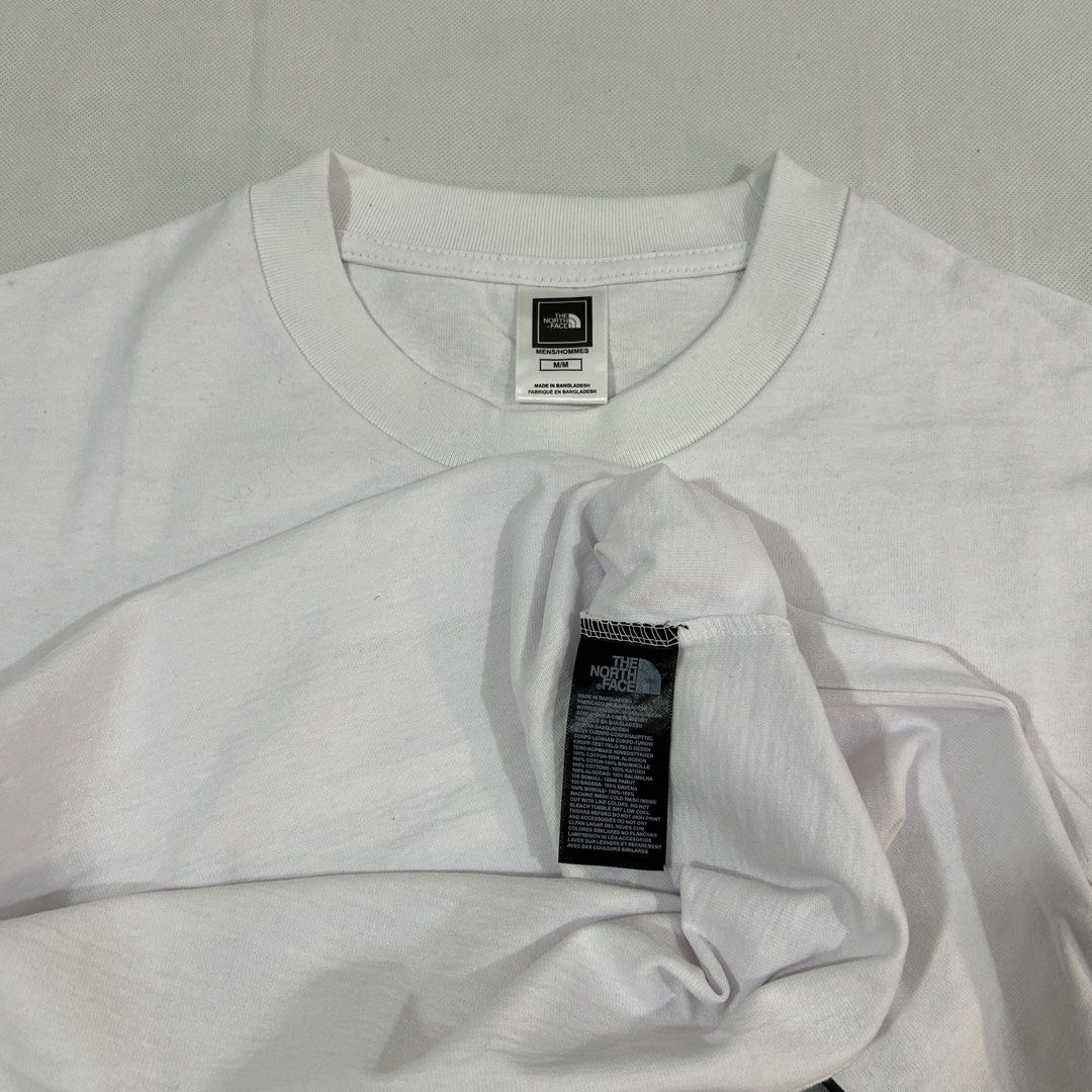 The North Face White Graphic T-Shirt Medium (Category: Tshirts & Polo Shirts ) located in Cavite. Submitted by moo2k (Listing ID 1469204358, Image 3). Description: - Brand: The North Face - Size: Medium (tag on collar) - Color: White - Design: Yellow dome logo on front, large grey brand text and yellow dome graphic on back - Fit: Short sleeves, standard crew neck - Condition: Clean fabric, no stains or wear detected.