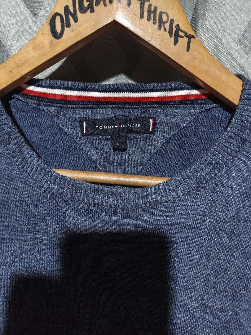 Tommy Hilfiger Blue Knit Sweater Size M (Category: Coats, Jackets and Outerwear) located in Maasim. Submitted by ukayganda25 (Listing ID 1469270912, Image 2). Description: - Brand: Tommy Hilfiger - Color: Dark blue marl knit - Size: Medium (20.5" pit to pit x 25" length) - Details: Ribbed collar with iconic red, white, and black stripes, embroidered chest logo - Condition: Clean overall, great pre-loved piece.