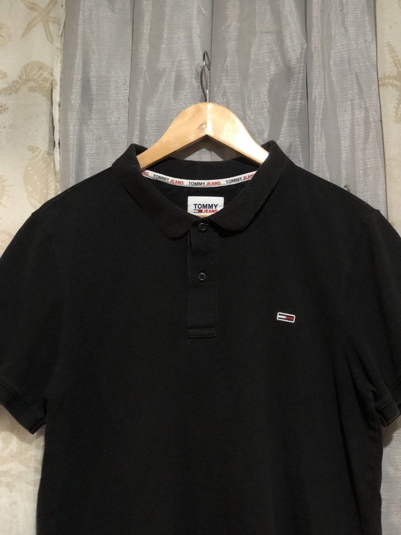 Tommy Jeans Black Polo Shirt (Category: Tshirts & Polo Shirts ) located in Calbayog City. Submitted by thriftme.bro (Listing ID 1469324470, Image 2). Description: Tommy Jeans black polo shirt with a classic collar and short sleeves. Features a two-button placket and branded inner collar tape. Small embroidered logo patch on the left chest. Ribbed cuffs and side hem slits. Made from soft cotton blend fabric. Clean look, goes with everything..